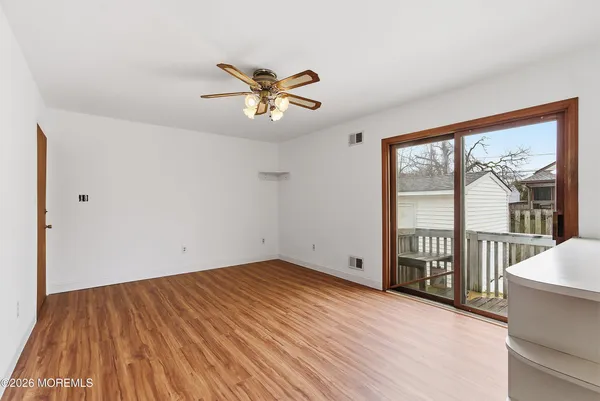 a view of an empty room with a window and wooden floor
