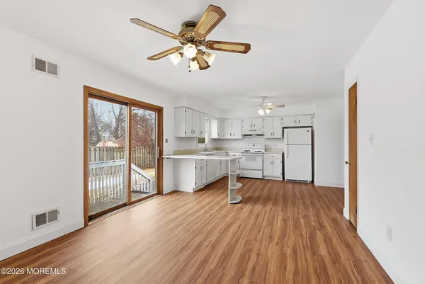 an empty room with wooden floor chandelier fan and windows