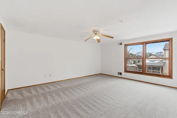 an empty room with wooden floor chandelier fan and windows
