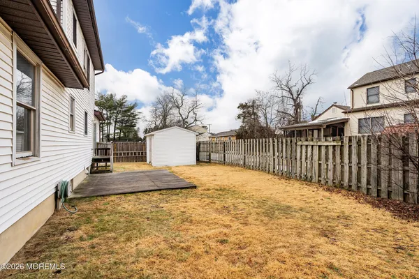 a view of a backyard with grass & fence