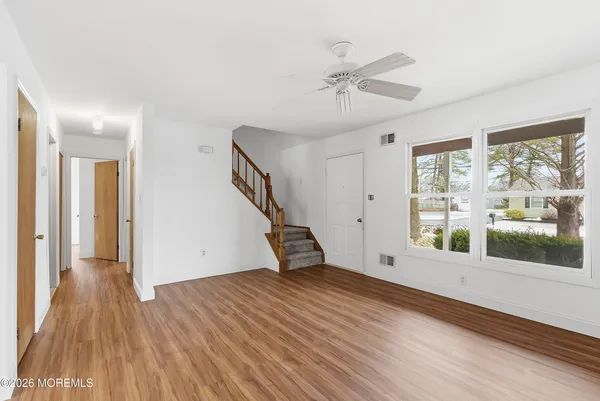 a view of empty room with wooden floor and fan