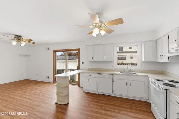 a large white kitchen with wooden floors and white walls