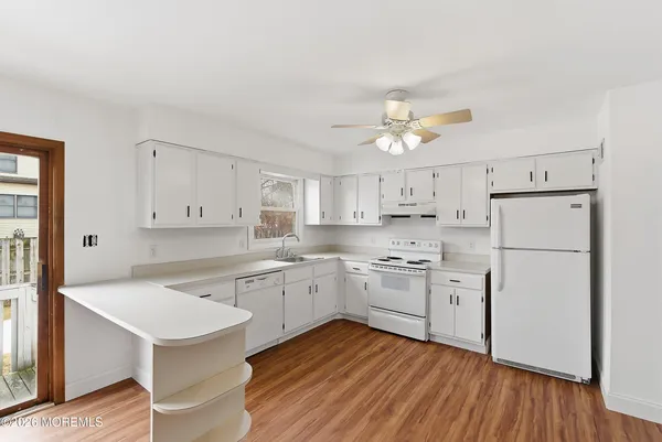 a kitchen with a sink a refrigerator and white cabinets