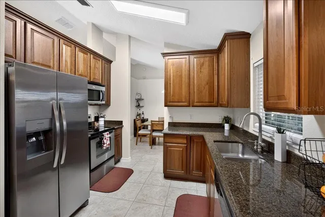 a kitchen with stainless steel appliances granite countertop a refrigerator a stove and a sink with wooden floor