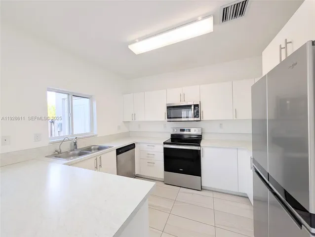 a large kitchen with stainless steel appliances a stove a refrigerator a sink and dishwasher