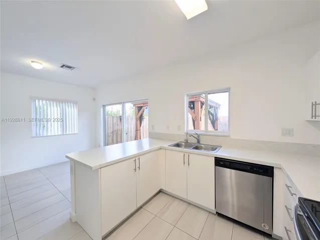 a kitchen with white cabinets appliances a sink and a window