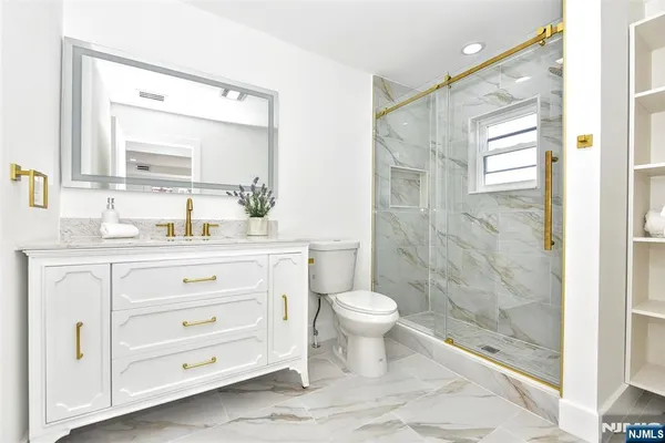 a bathroom with a sink a toilet a mirror and shower