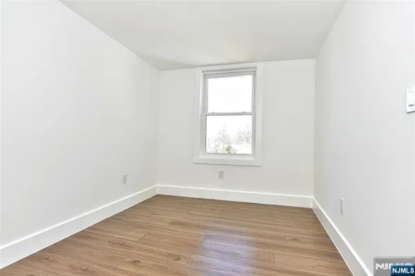 an empty room with wooden floor and window