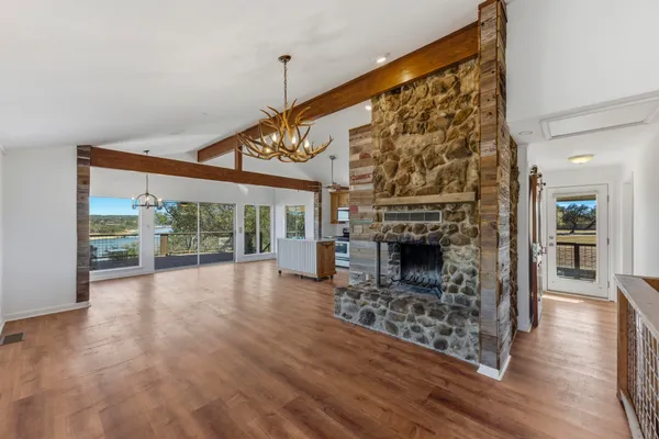 a view of an empty room with wooden floor fireplace and a window