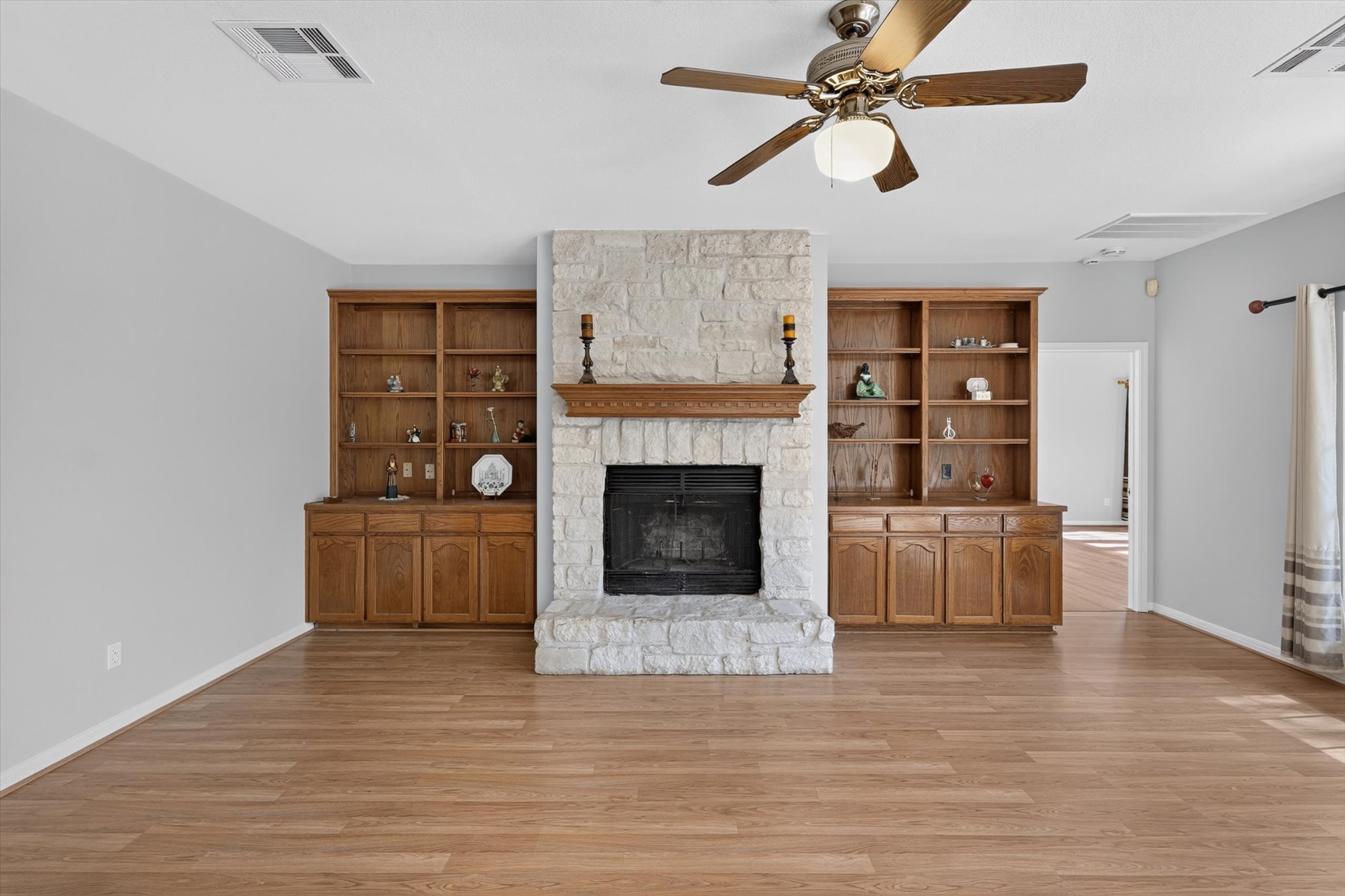 13615 Copperleaf Trail Manchaca, TX 78652 - Photo 14 of 38 A striking stone fireplace is flanked by custom built-in cabinetry and warm wood flooring.