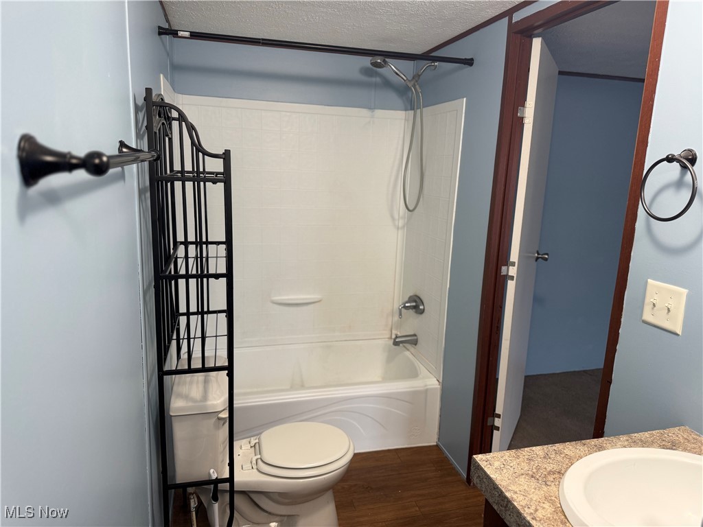 20 Eddie Road Madison, OH 44057 - Photo 6 of 9 Full bathroom with vanity, shower combination, a textured ceiling, and dark wood finished floors