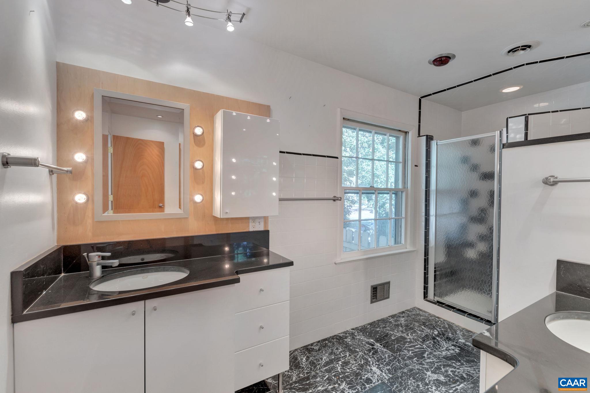 1406 Holly Road Charlottesville, VA 22901 - Photo 39 of 62 a bathroom with a double vanity sink a toilet a mirror and shower
