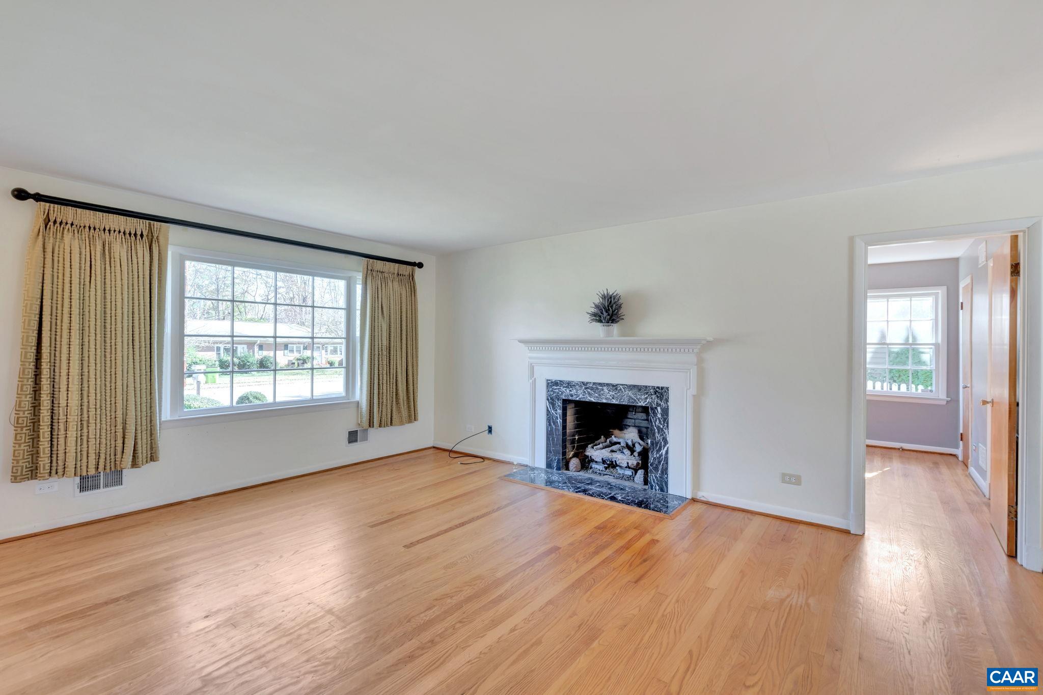1406 Holly Road Charlottesville, VA 22901 - Photo 10 of 62 an empty room with wooden floor fireplace and windows