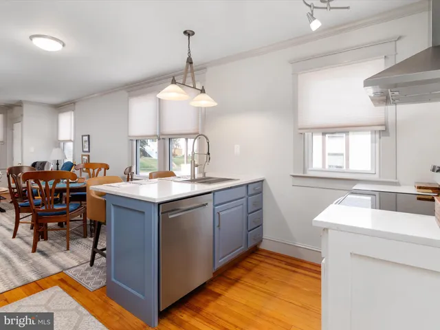 a kitchen with stainless steel appliances granite countertop a sink dishwasher a stove a dining table and chairs with wooden floor