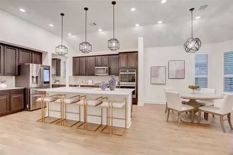 a large kitchen with granite countertop a stove a sink a island and chairs