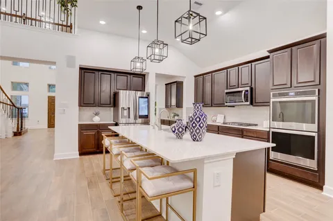 a kitchen with stainless steel appliances kitchen island granite countertop a refrigerator a stove a microwave oven a sink with island and chairs