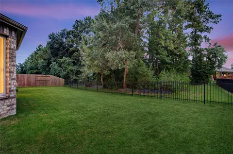 a view of a backyard with a trees and wooden fence