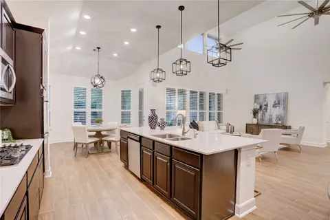 a large kitchen with a counter space a sink appliances and living room view