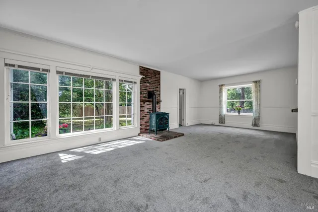a view of an empty room with a fireplace and a window