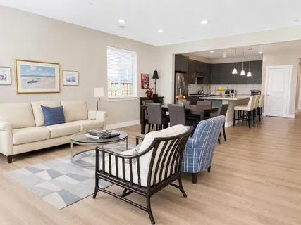 a living room with furniture a rug and kitchen view