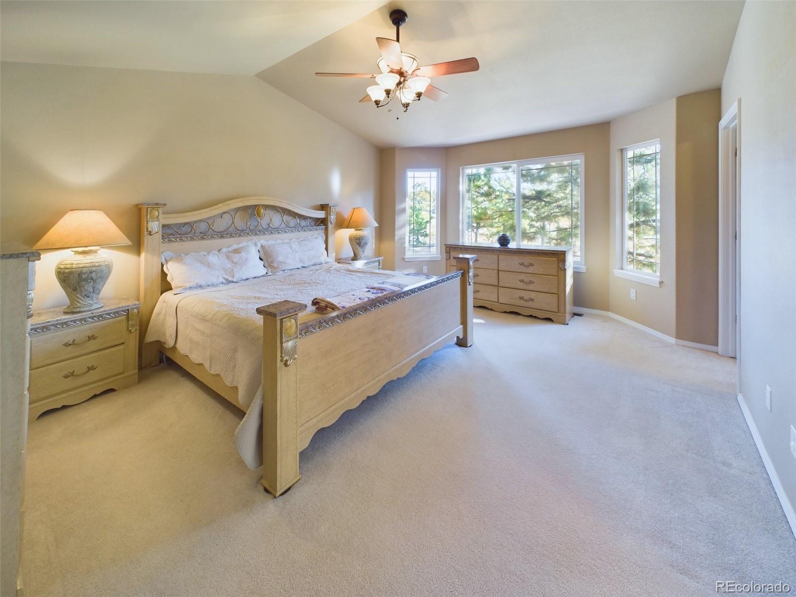 5140 Shoup Road Colorado Springs, CO 80908 - Photo 9 of 42 a spacious bedroom with a bed and a chandelier