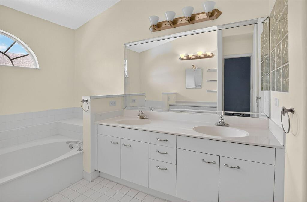 5051 Pointe Emerald Lane, Unit 5051 Boca Raton, FL 33431 - Photo 25 of 65 a bathroom with a double vanity sink mirror and bathtub