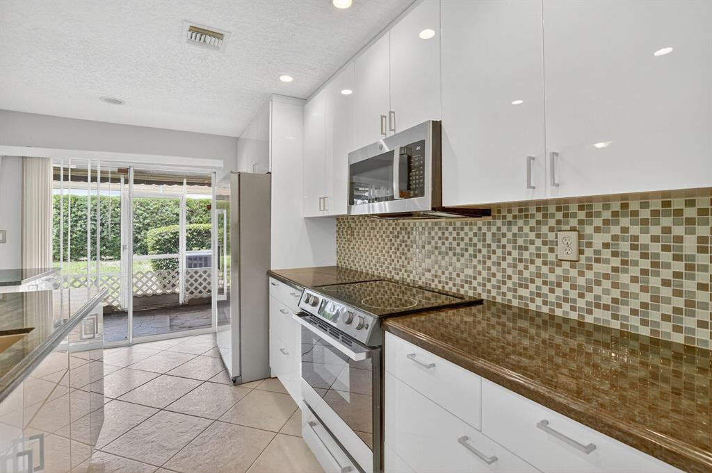 5051 Pointe Emerald Lane, Unit 5051 Boca Raton, FL 33431 - Photo 8 of 65 a kitchen with a sink a stove and cabinets