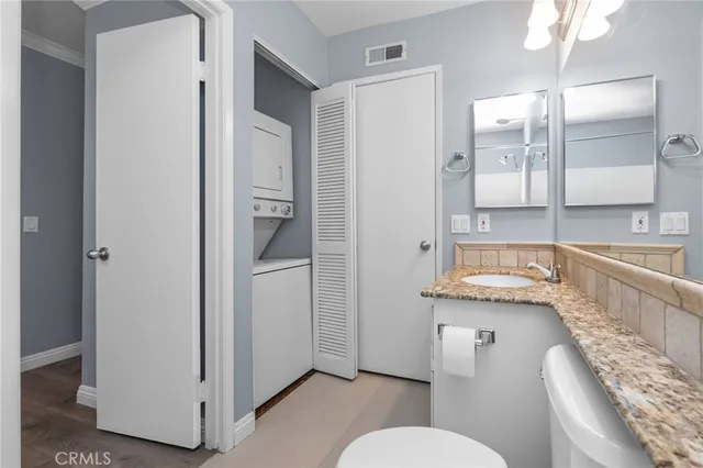 a bathroom with a granite countertop sink a toilet a mirror and shower