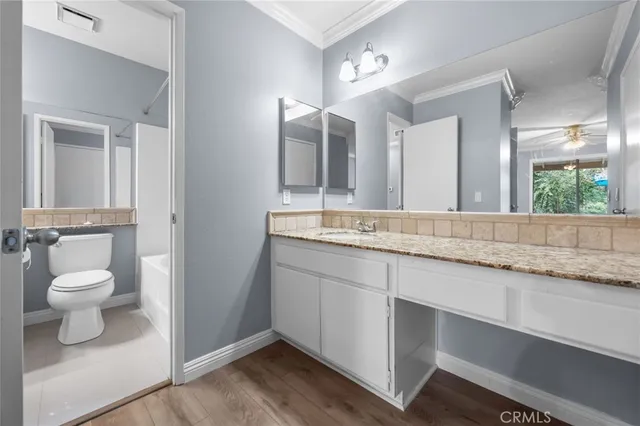 a spacious bathroom with a granite countertop sink a toilet and a mirror