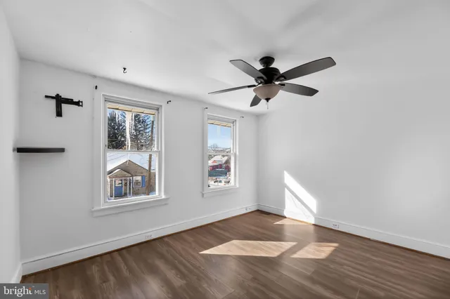 a view of an empty room with window and wooden floor