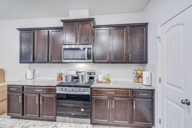 a kitchen with stainless steel appliances granite countertop a sink stove and cabinets