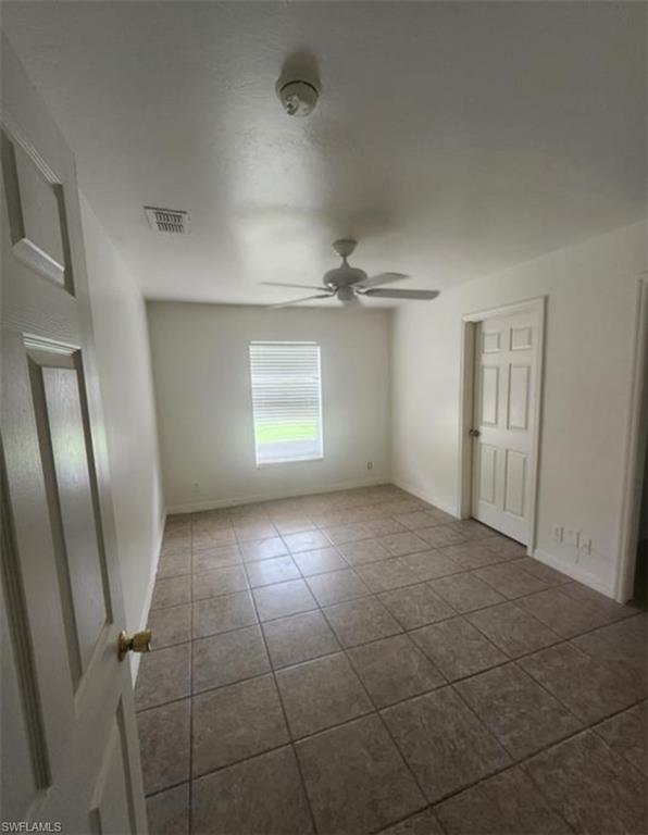 1854 55th Terrace Southwest Naples, FL 34116 - Photo 4 of 9 Unfurnished bedroom featuring ceiling fan and dark tile patterned flooring