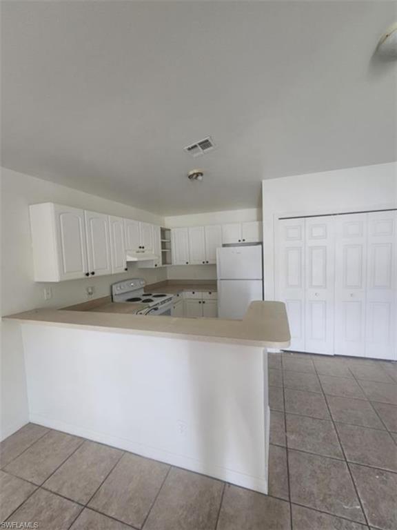 1854 55th Terrace Southwest Naples, FL 34116 - Photo 9 of 9 Kitchen with white appliances, light tile patterned flooring, a peninsula, and light countertops