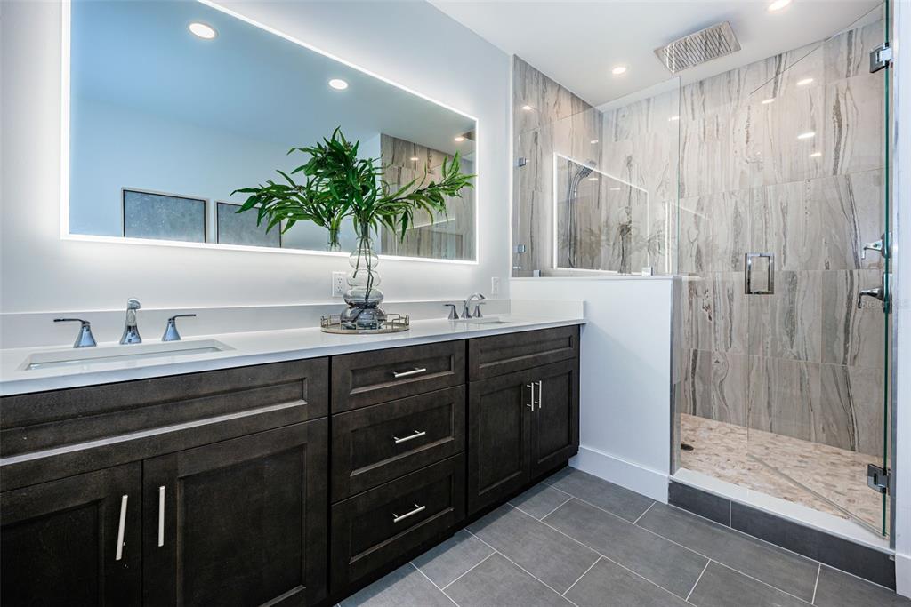 12305 3rd Street East, Unit 2 Treasure Island, FL 33706 - Photo 43 of 69 a bathroom with a granite countertop sink a mirror and a shower