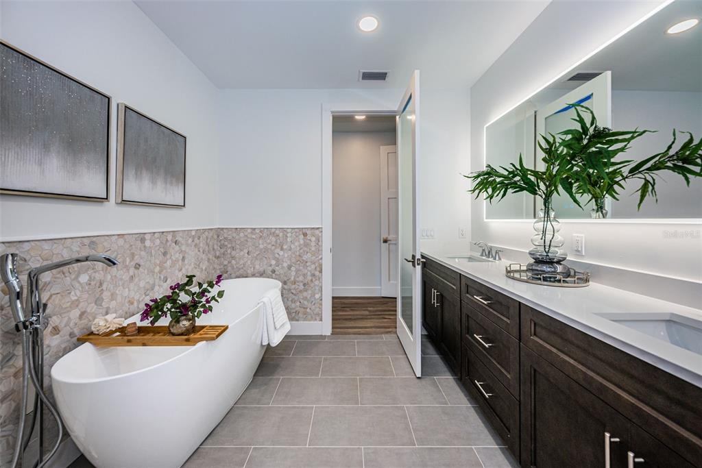 12305 3rd Street East, Unit 2 Treasure Island, FL 33706 - Photo 44 of 69 a spacious bathroom with a double vanity sink a large mirror and a bathtub