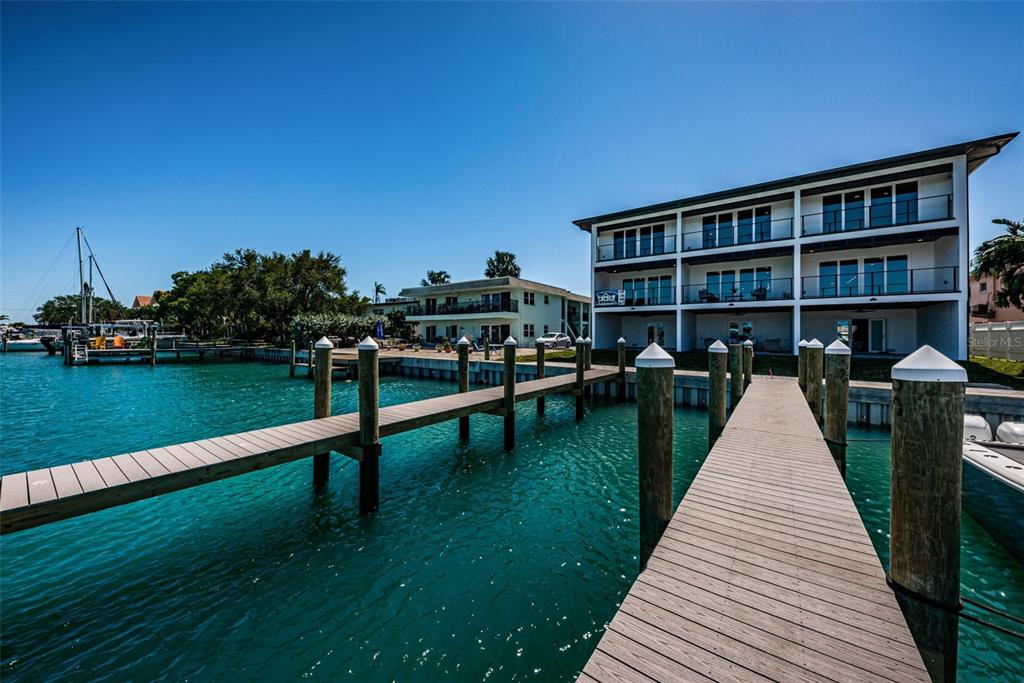 12305 3rd Street East, Unit 2 Treasure Island, FL 33706 - Photo 65 of 69 a view of swimming pool with lawn chairs wooden floor and fence