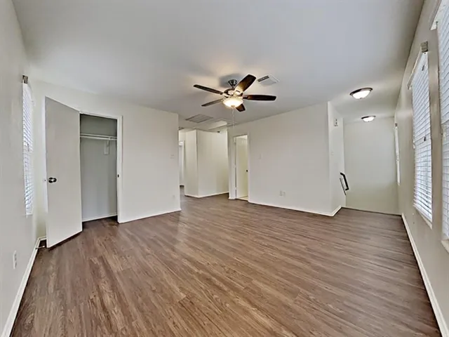 an empty room with wooden floor and a ceiling fan