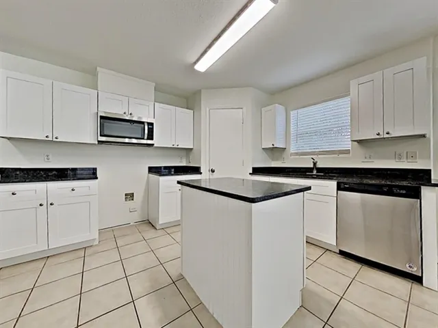a kitchen with stainless steel appliances granite countertop a sink a stove a microwave and cabinets