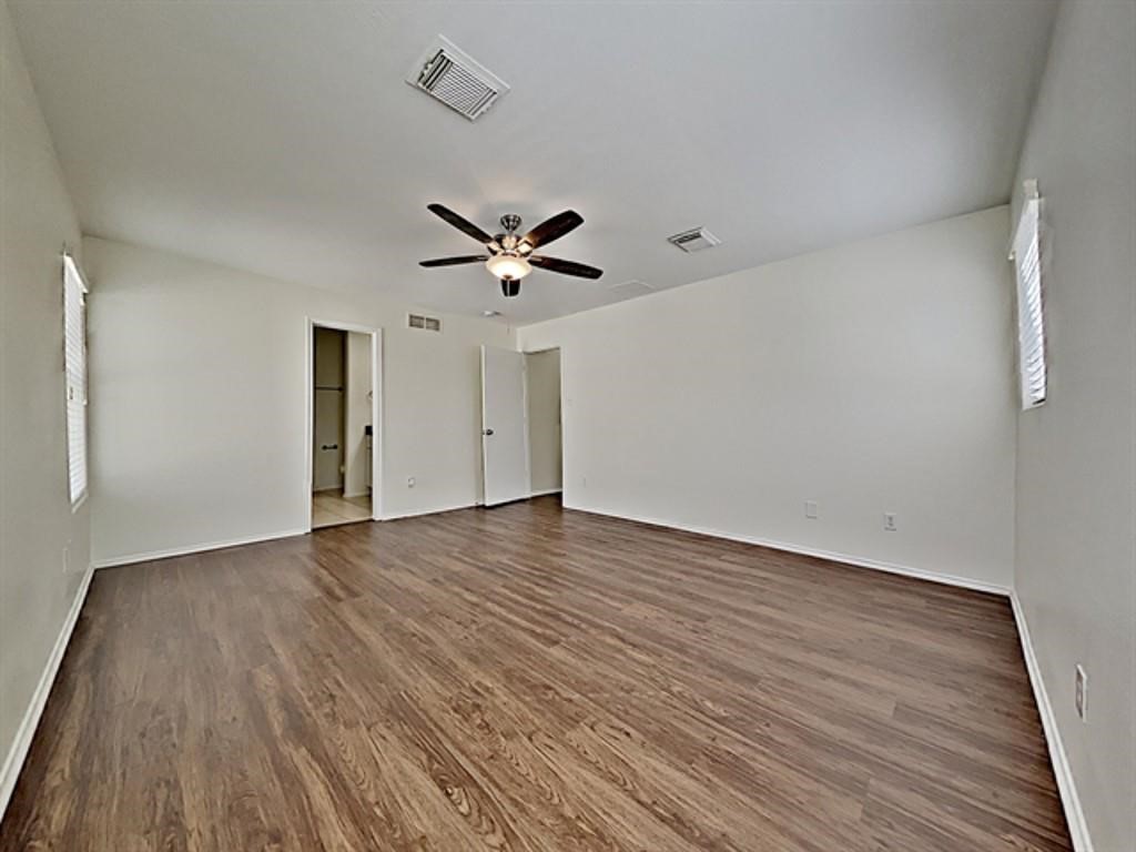 6830 Shallow River Court Spring, TX 77379 - Photo 9 of 17 a view of an empty room with wooden floor and a ceiling fan