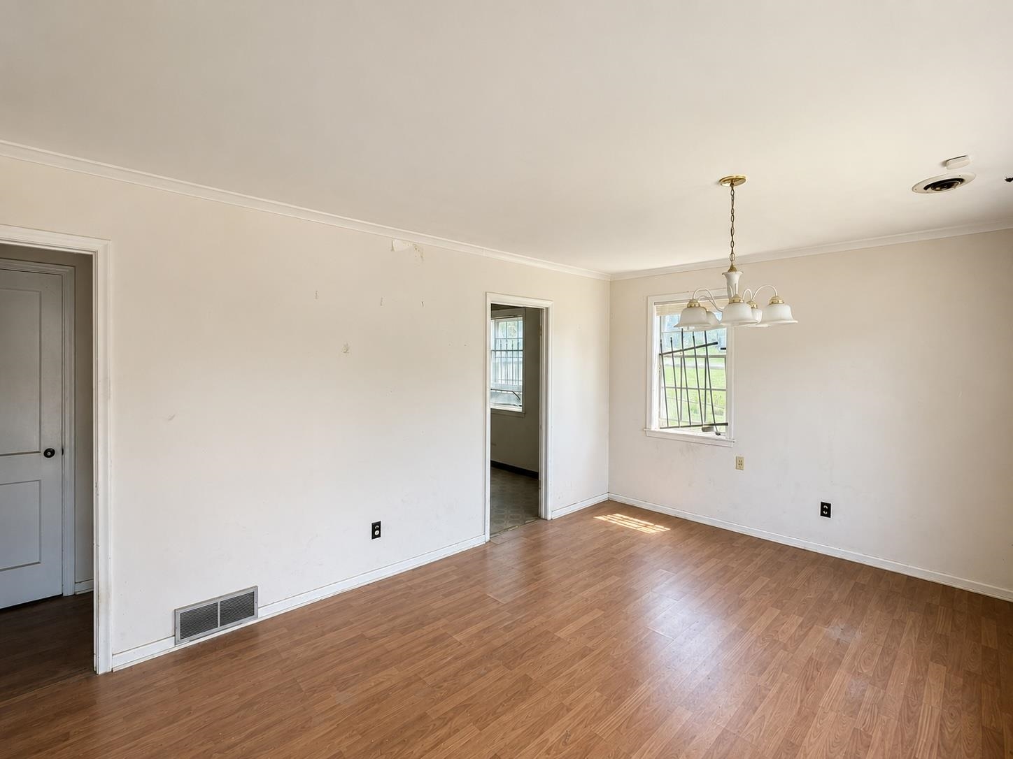 Wood-finish flooring with crown molding and a multi-light ceiling fixture