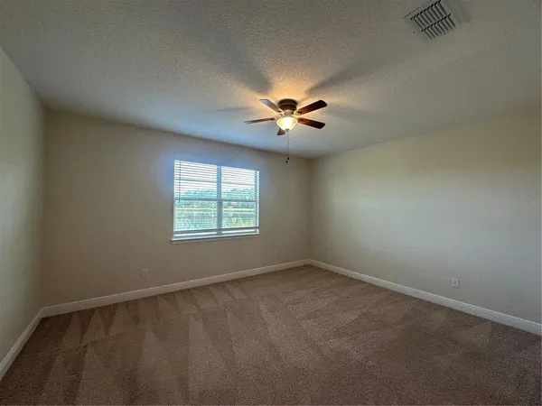 an empty room with a window and a fan