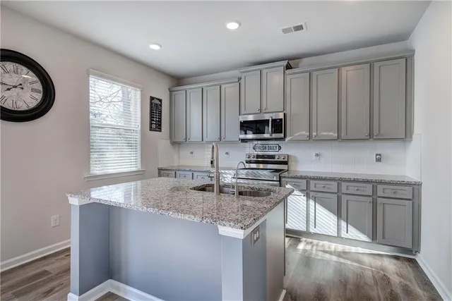 a kitchen with kitchen island granite countertop a sink a stove cabinets and a window