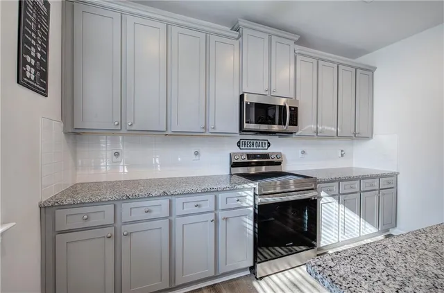 a kitchen with granite countertop white cabinets and stainless steel appliances