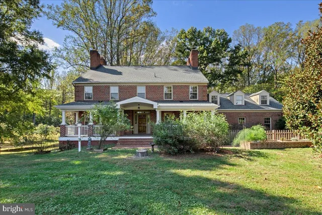 a front view of a house with a garden and trees