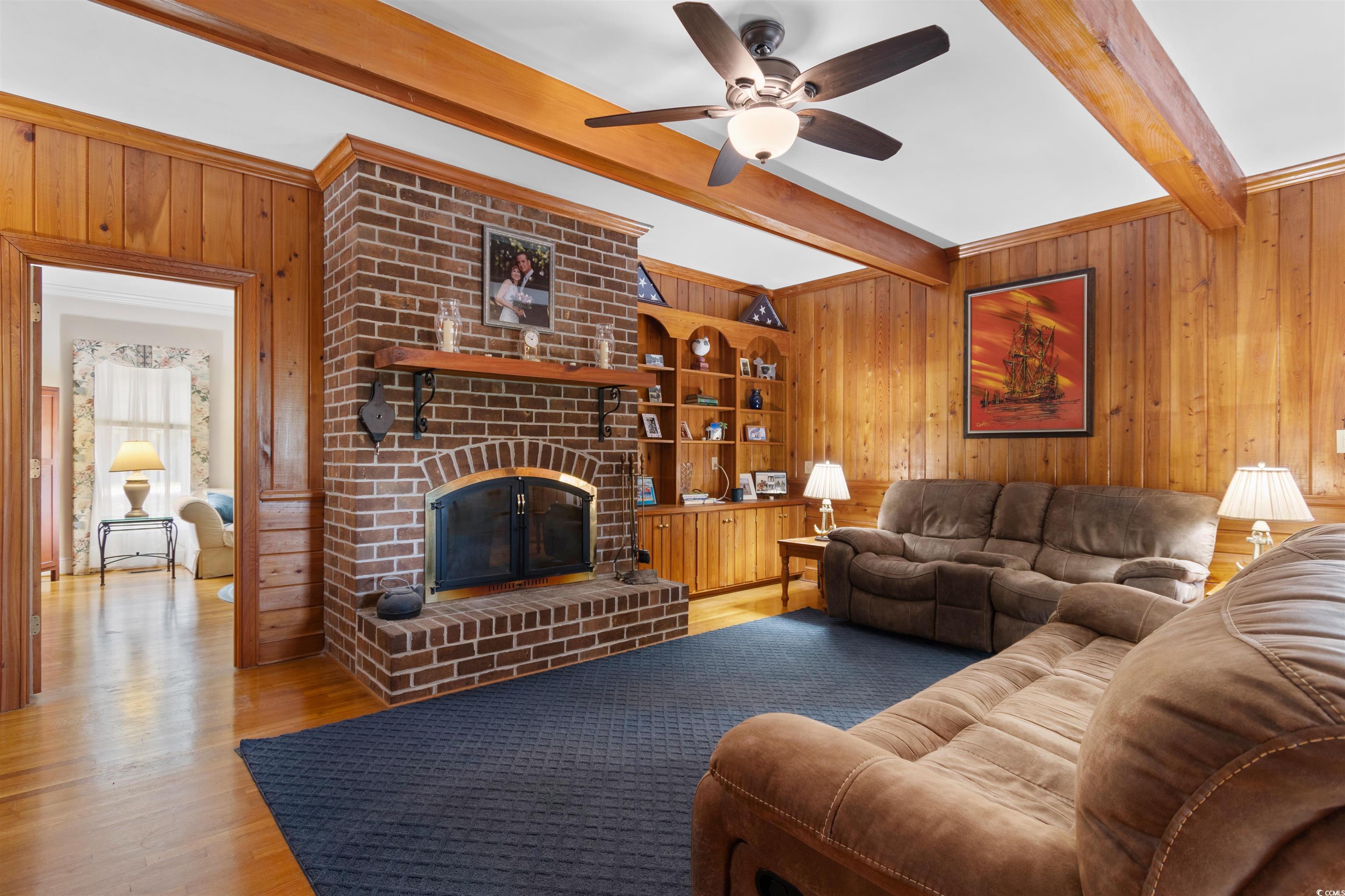 14 Live Oak Lane Georgetown, SC 29440 - Photo 11 of 40 Living room with wood walls, beamed ceiling, a fireplace, original hardwood floors, and ceiling fan