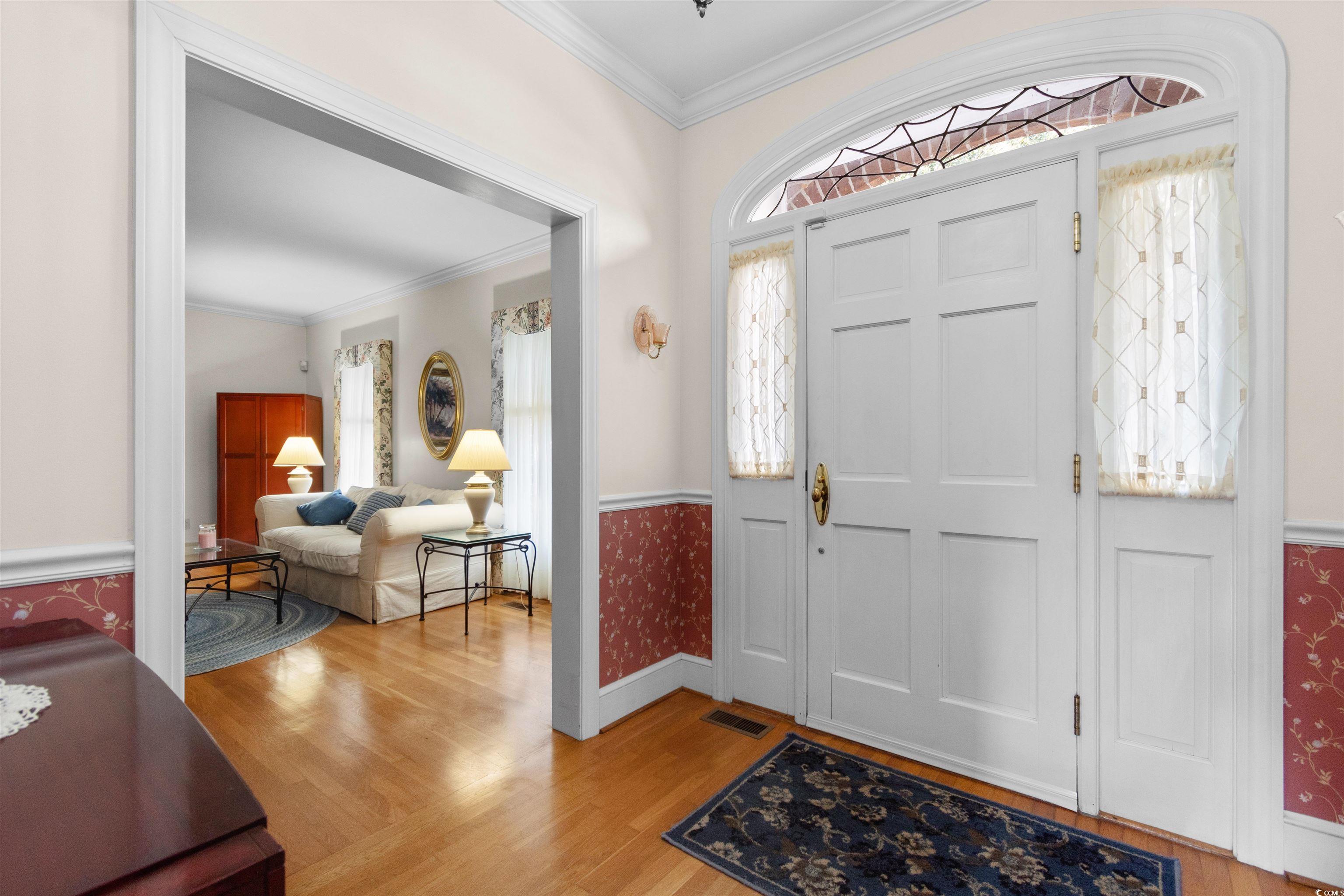 14 Live Oak Lane Georgetown, SC 29440 - Photo 5 of 40 Foyer entrance featuring ornamental molding, light wood-style flooring, plenty of natural light, wainscoting, and wallpapered walls
