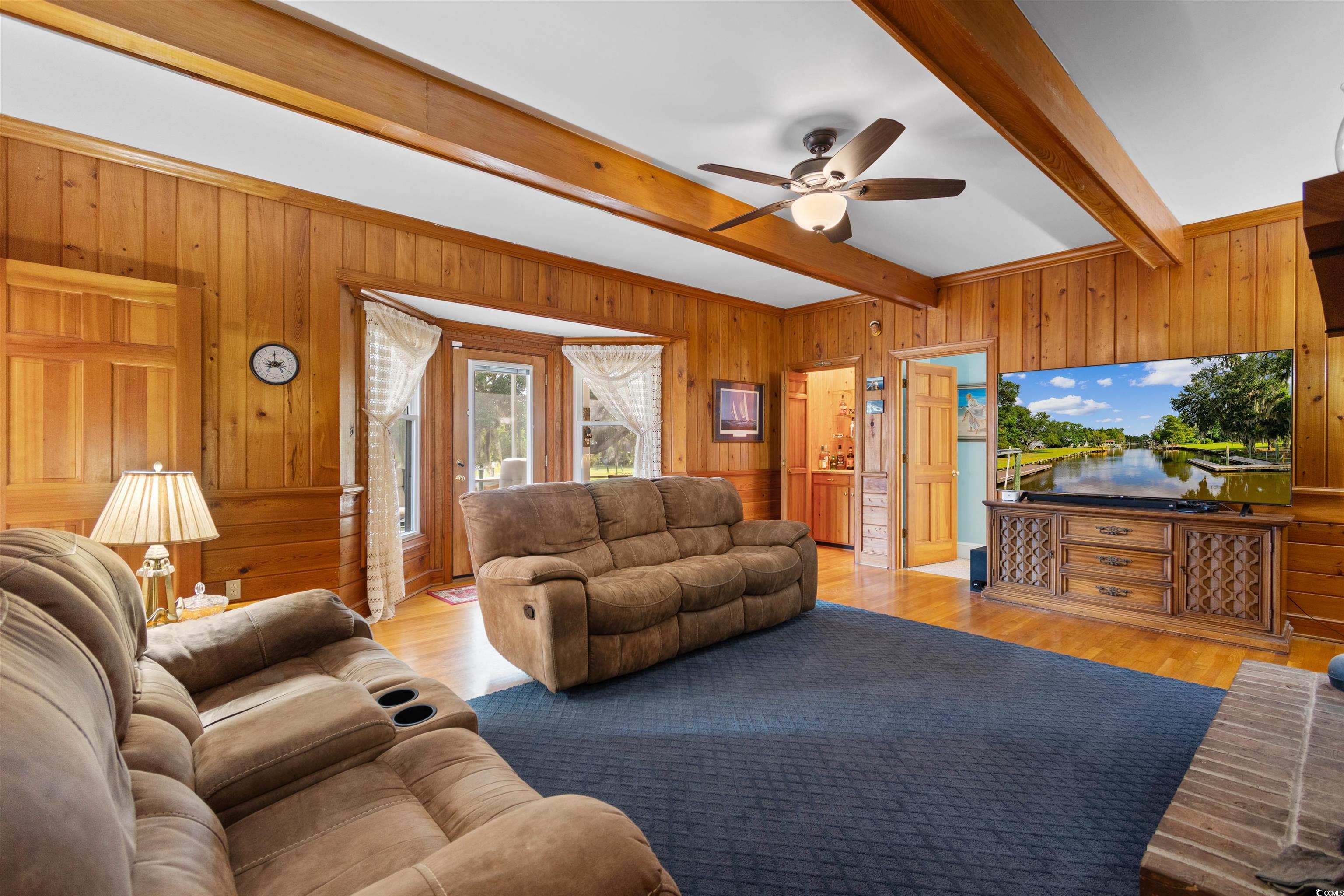14 Live Oak Lane Georgetown, SC 29440 - Photo 10 of 40 Living area featuring wooden walls, beam ceiling, ceiling fan, and original hard wood flooring.