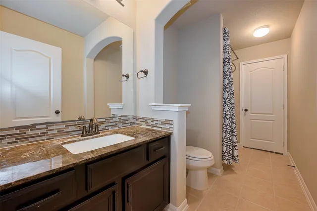 a bathroom with a granite countertop sink a toilet and a mirror
