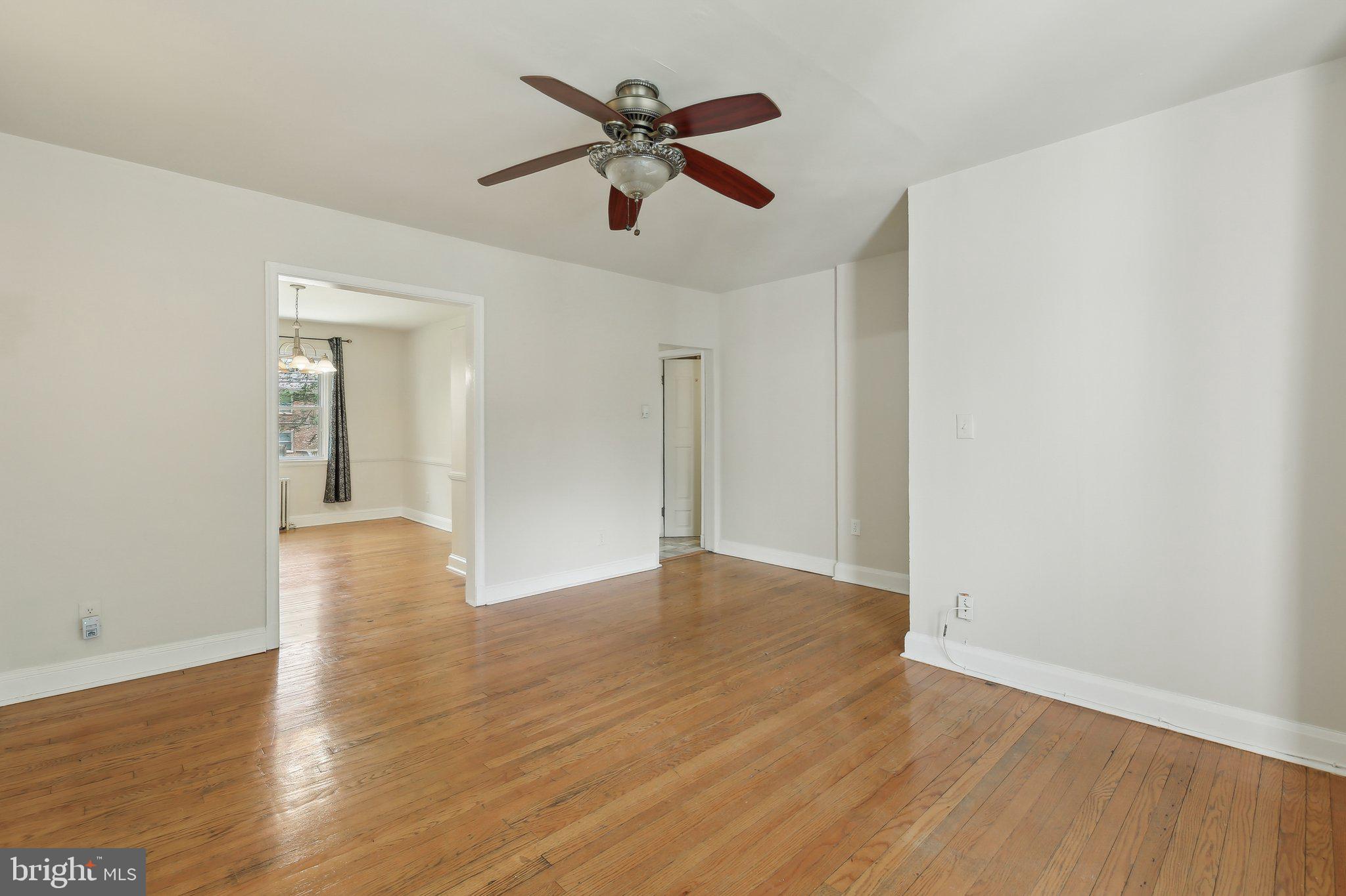 5509 Lothian Road Baltimore, MD 21212 - Photo 8 of 31 an empty room to hallway with wooden floor a ceiling fan and a window