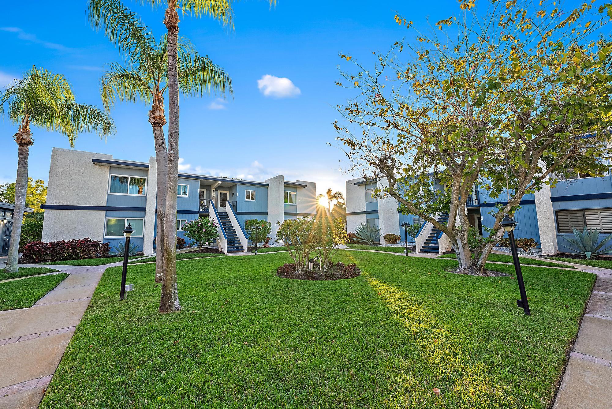 a view of a house with a big yard and palm trees